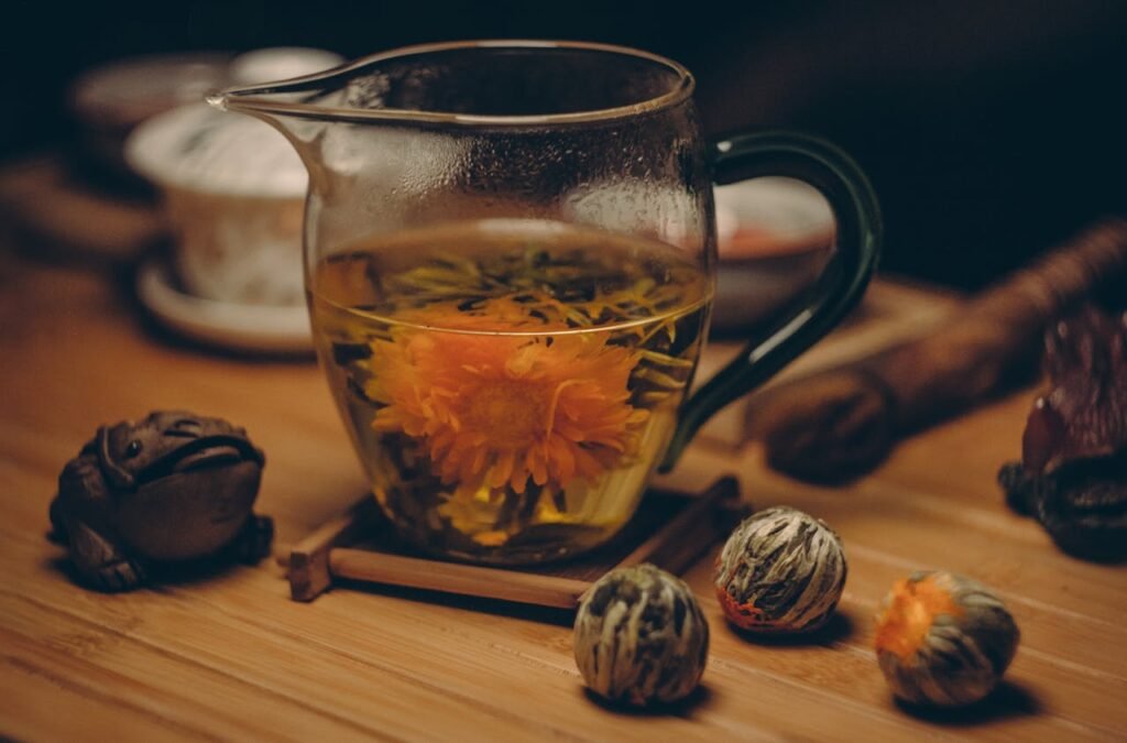 Orange Petaled Flowers in Clear Glass Pitcher With Water on Brown Table Close Up Photography